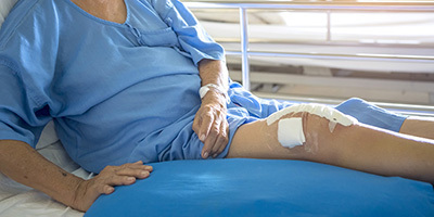 Resident in a bed with a clean bandage on a knee wound.